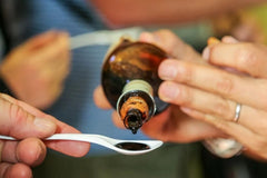 Balsamic vinegar being poured into a tasting spoon